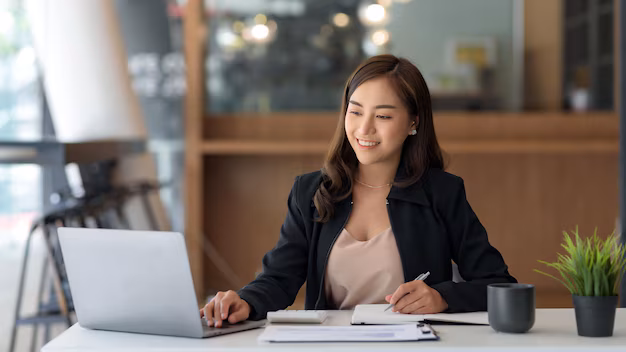 beautiful-young-asian-businesswoman-is-smiling-her-desk-taking-notes-with-computer-laptop-her-desk-enjoying-work_37714-2112