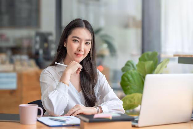 successful-smiling-beautiful-young-asian-businesswoman-sitting-with-laptop-computer-while-doing-some-paperwork-office-looking-camera_37714-1890